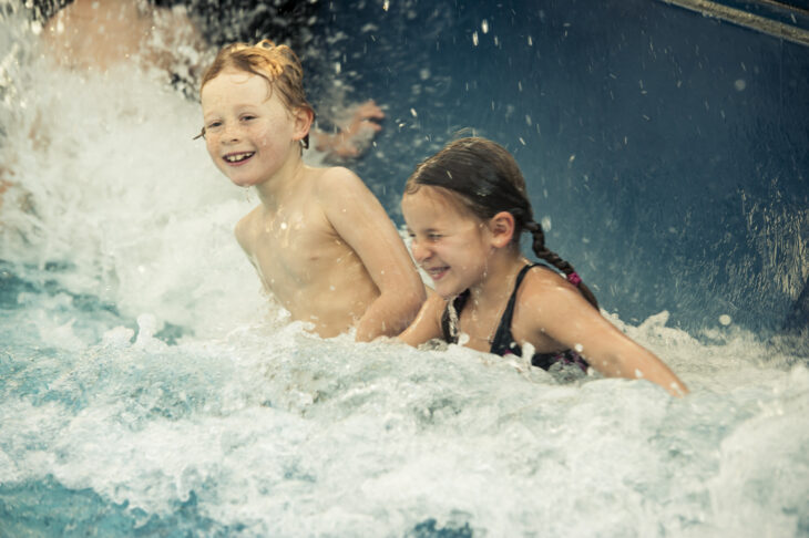 Zwei Kinder im Hallenbad. Sie spielen in den Wellen.