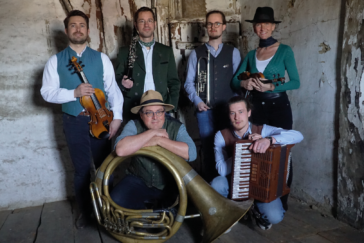 Eine Band, bestehend aus sechs Menschen, posiert mit ihren volkstümlichen Instrumenten.